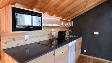A modern kitchen with wooden cabinetry, a black countertop, and a built-in microwave.