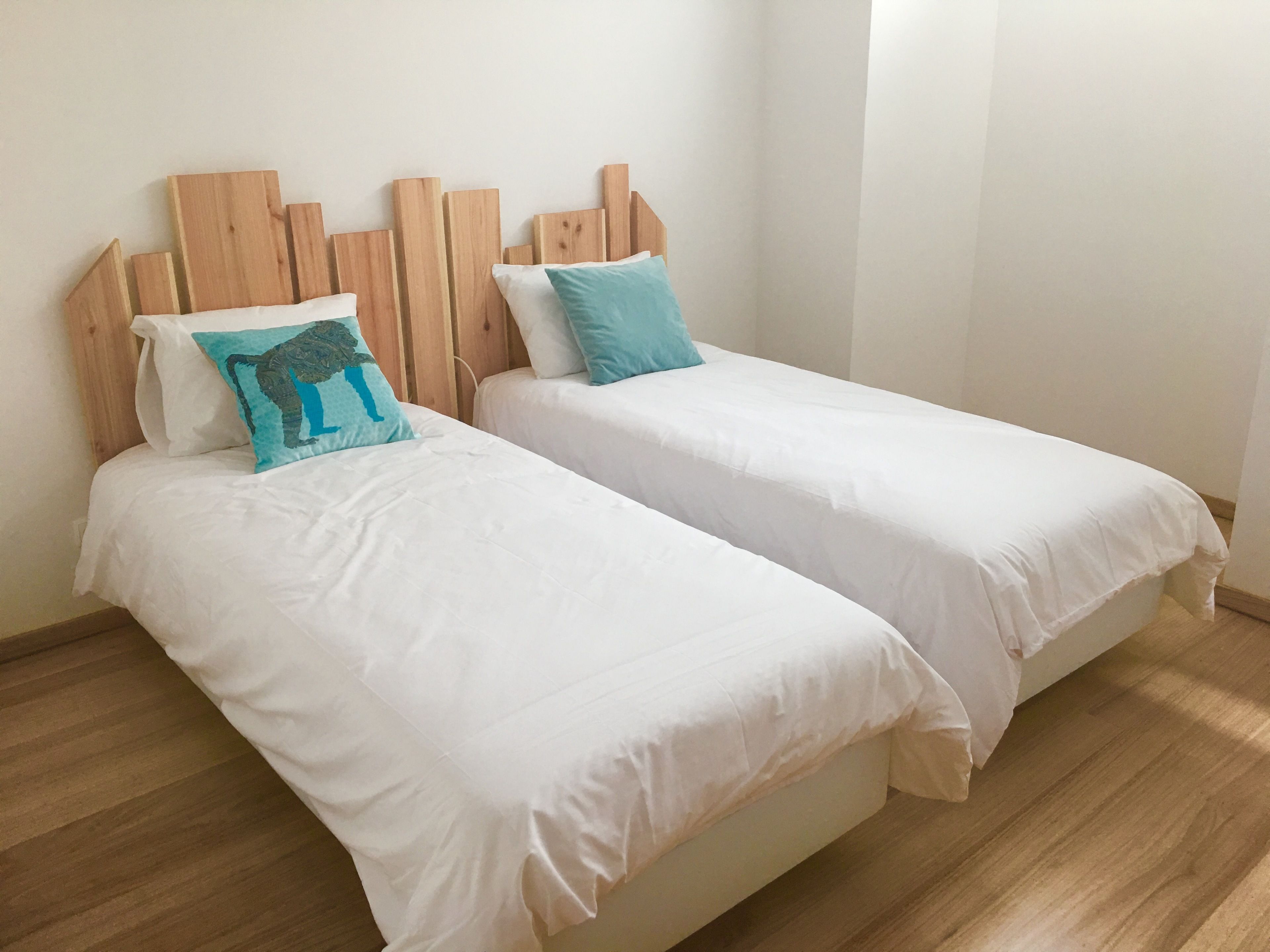 Two single beds with wooden headboards, white bedding, and a wooden floor.