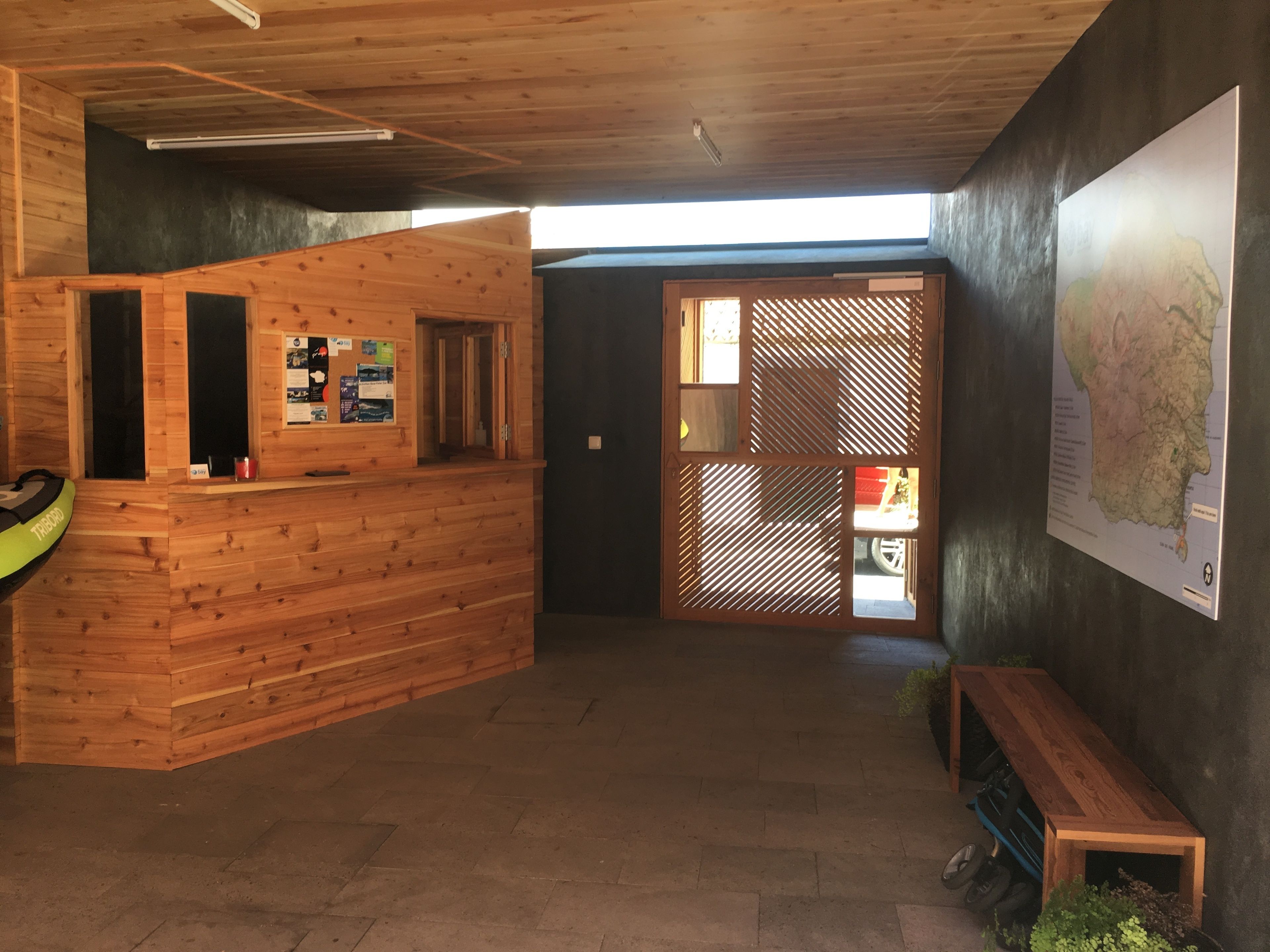 Ein Empfangsbereich mit einem Holztisch, einer Karte an der Wand und einer Sitzbank.