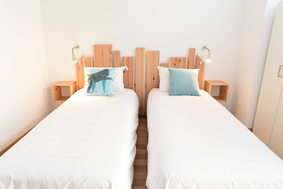 Two single beds with wooden headboards and bedside tables, each with a lamp.
