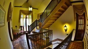 A staircase with a wooden railing, a dining area with a table and chairs, and a wall-mounted light fixture. - Pousada Estalagem de Brotas (Brotas)