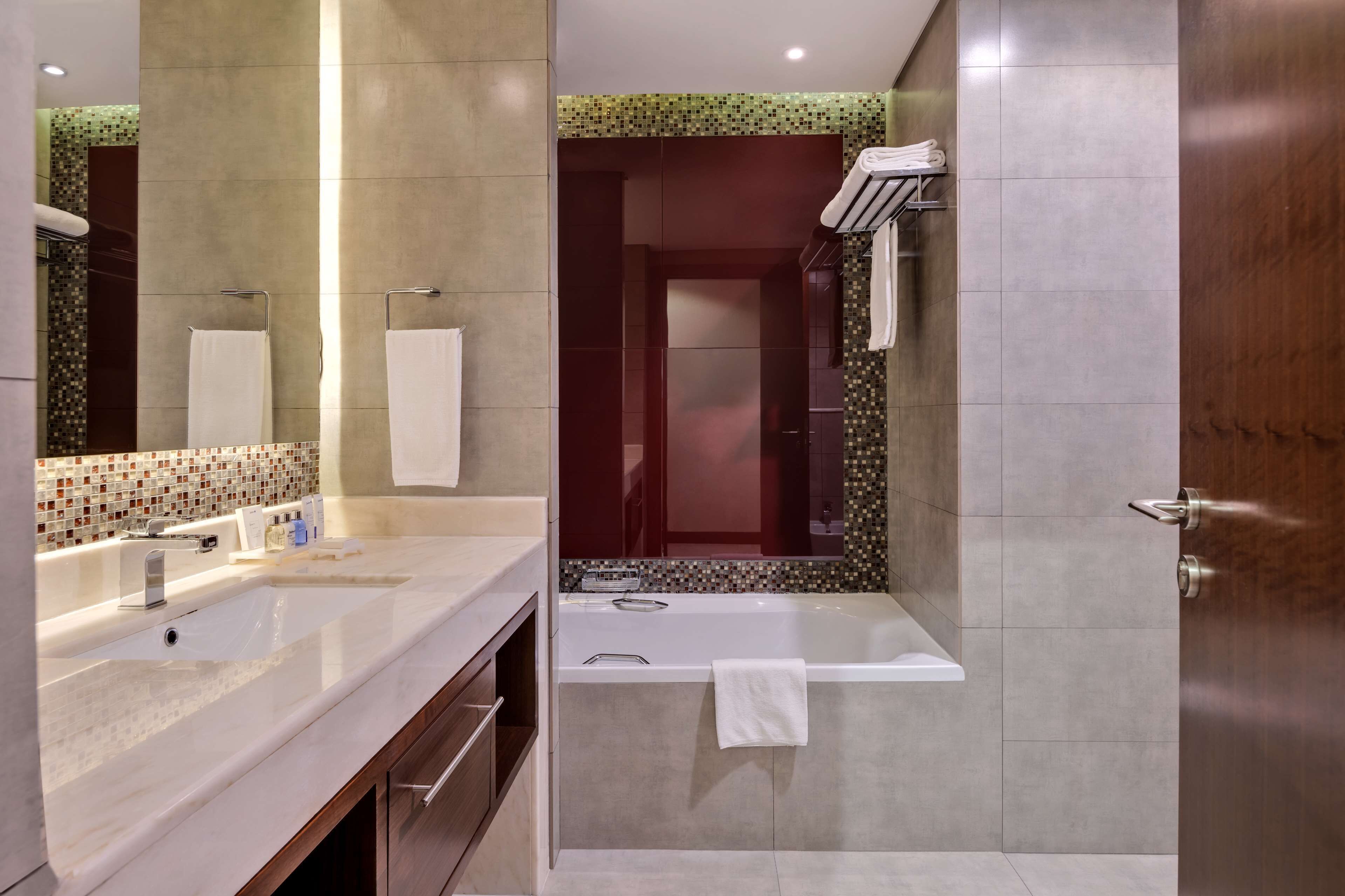 Un baño moderno con un espejo grande, dos lavamanos, una bañera y una zona de ducha.