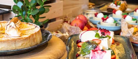 A variety of desserts on wooden serving boards, including a cheesecake and fruit-topped desserts.