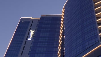 A modern high-rise building with a curved glass facade and illuminated horizontal lines.