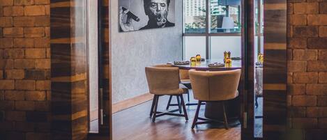 Un área de comedor moderna con una pared de ladrillo, un ventanal que da a un balcón y una mesa con platos y vasos.