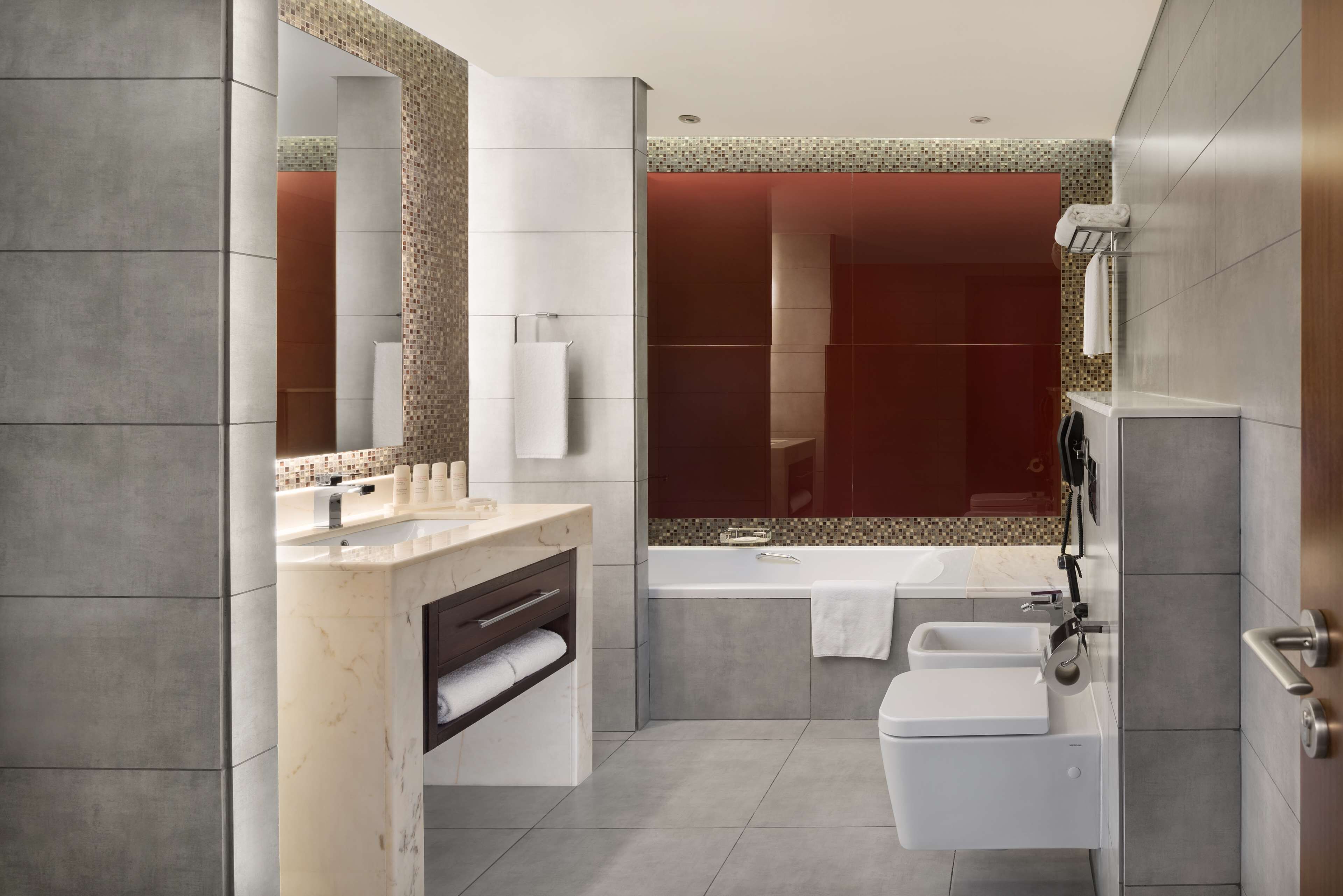 Et moderne badeværelse med en marmorvask, et badekar, et toilet og en bruseniche.