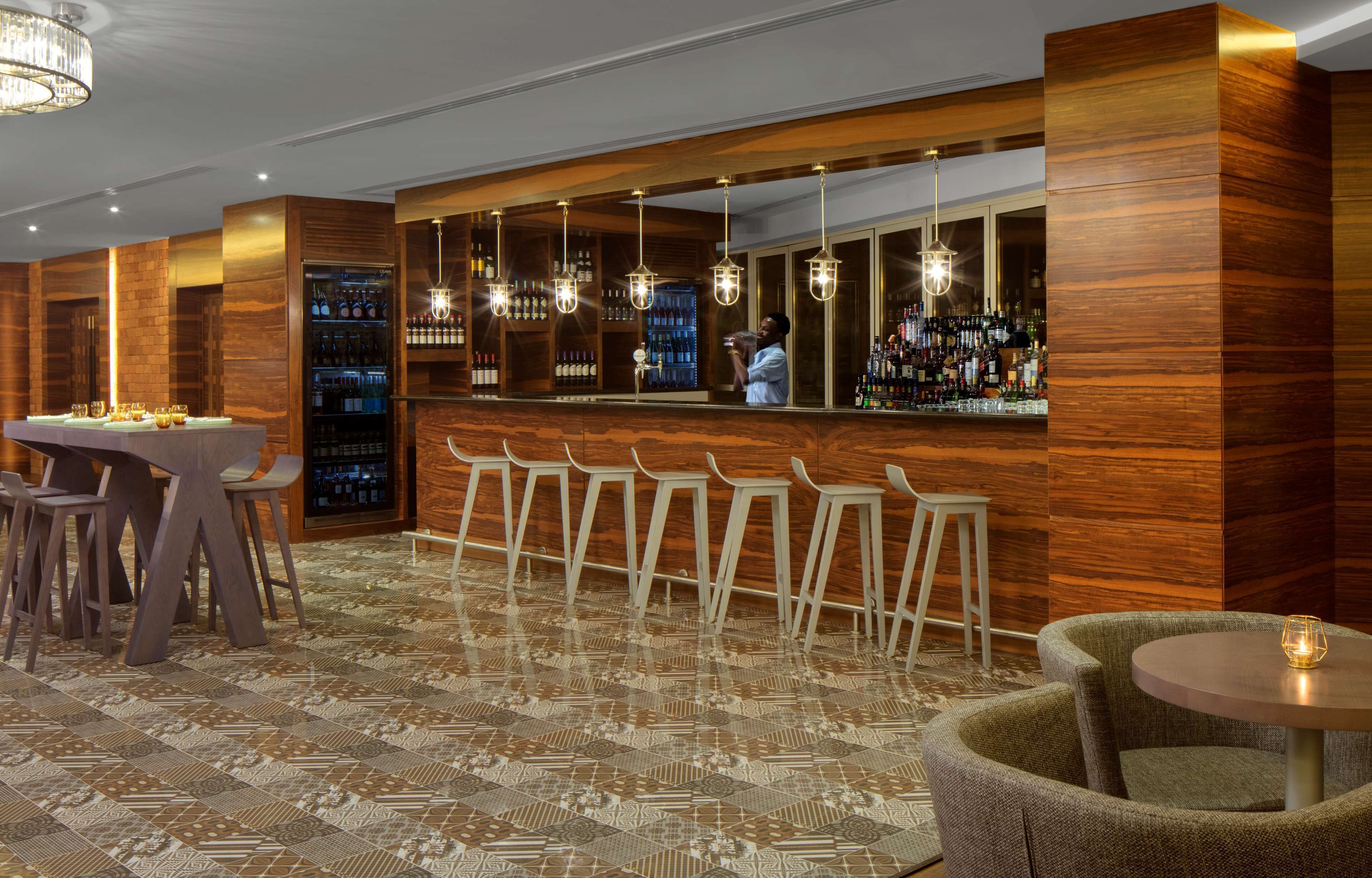 A bar area with wooden paneling, bar stools, and a bartender.