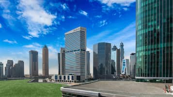 A cityscape with modern high-rise buildings, a grassy area, and a body of water.