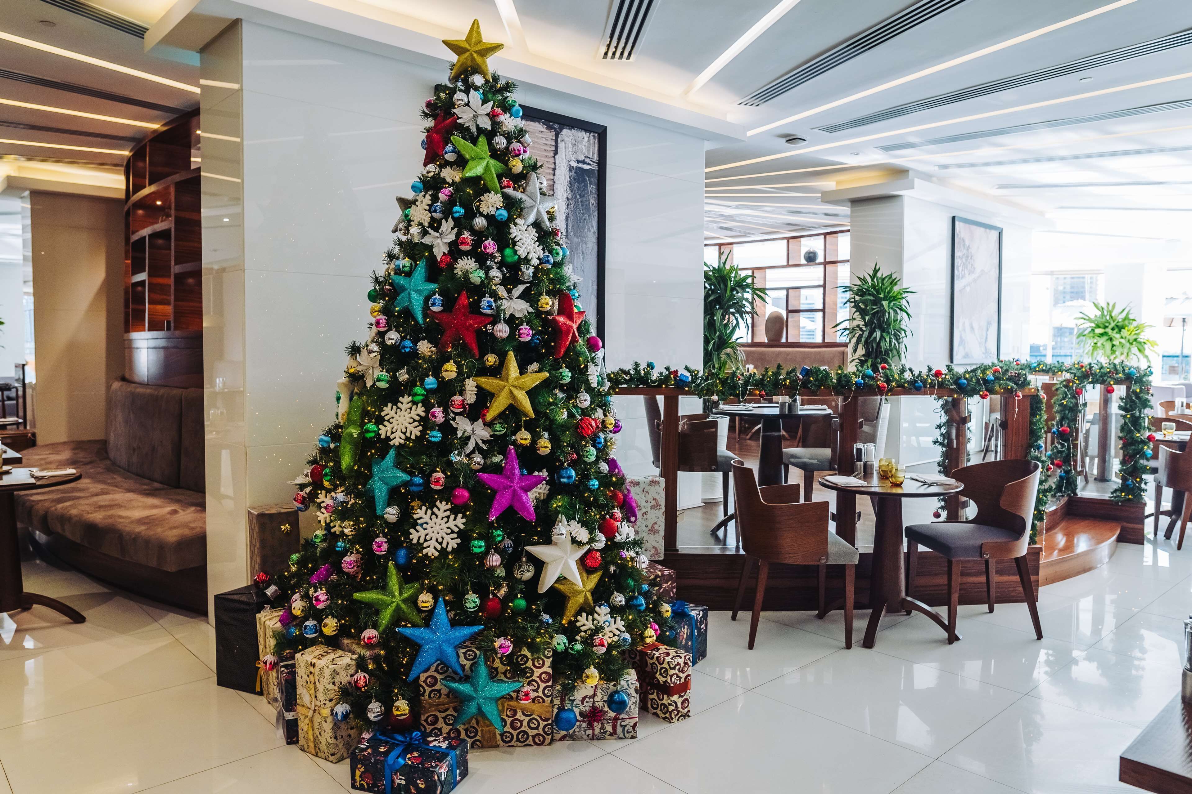 A Christmas tree in a hotel lobby with wrapped presents underneath.