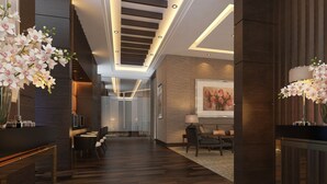 Eine moderne Hotelhalle mit Holzboden, einer Rezeption, einer Sitzecke und einer Treppe.