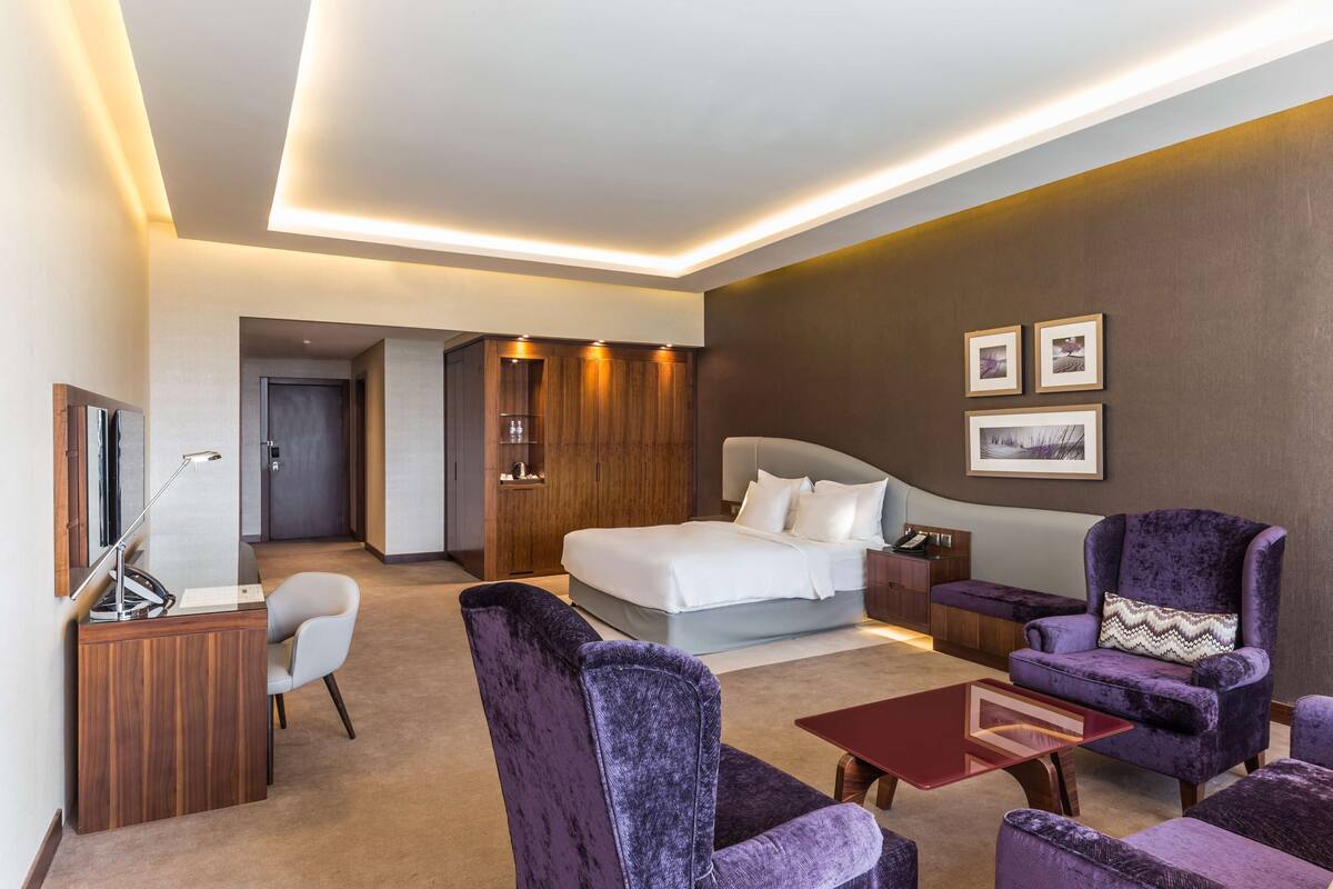 Ein modernes Hotelzimmer mit Bett, Schreibtisch, Stuhl, Sofa und Couchtisch.