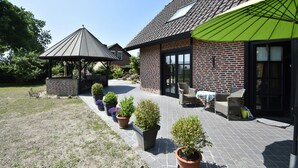 Ein Backsteinhaus mit Terrasse, Blumentöpfen und Gartenmöbeln.
