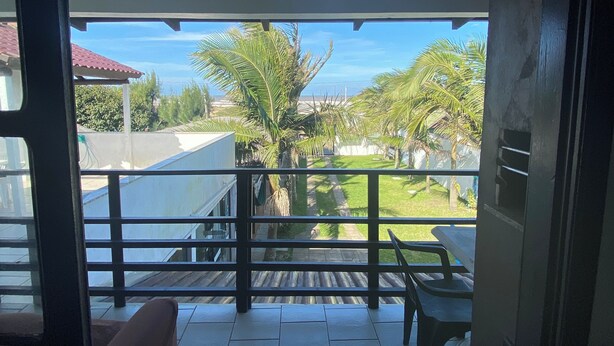 A balcony with a tiled floor, a table, and chairs. - Pousada Aventura (Passo de Torres)