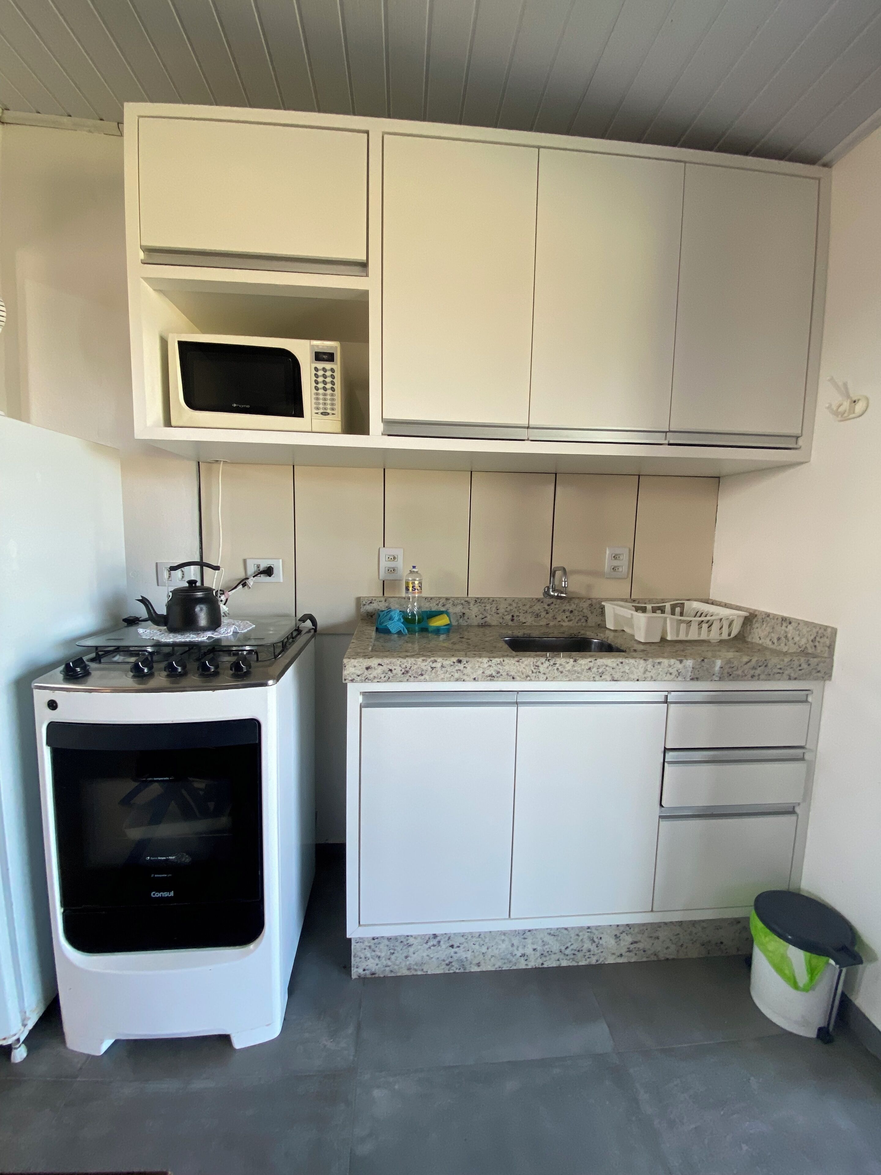 A compact kitchen with white cabinets, a microwave, a stove, and a sink.