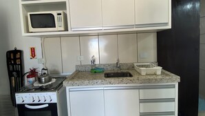 A kitchen with white cabinets, a microwave, a stove, and a sink. - Pousada Aventura (Passo de Torres)