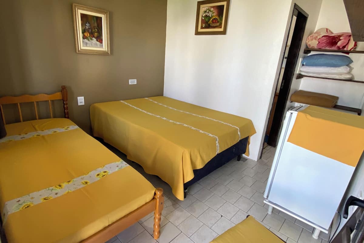 Ein Zimmer mit zwei Betten, einem kleinen Tisch und einem Stuhl.
