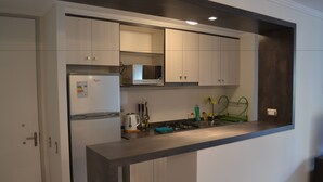 A modern kitchen with a built-in microwave, a kettle, and a gas stove. - Apartamentos Alma Surire (Arica)