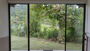 Una habitación con un amplio ventanal corredera que da a un jardín exuberante.