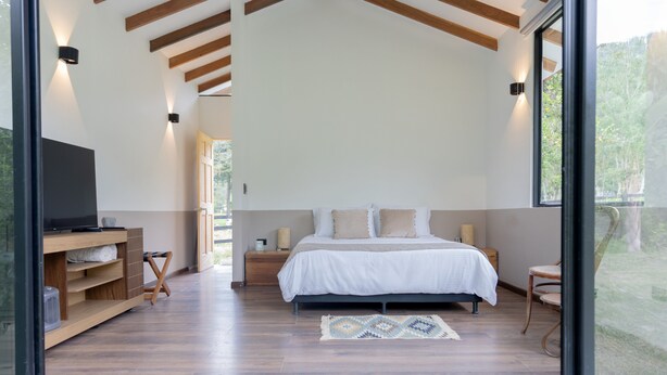 Un dormitorio moderno con una cama grande, suelo de madera y un televisor en un estante empotrado.