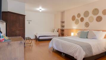 A bedroom with two beds, wooden flooring, a wardrobe, and wall decorations.
