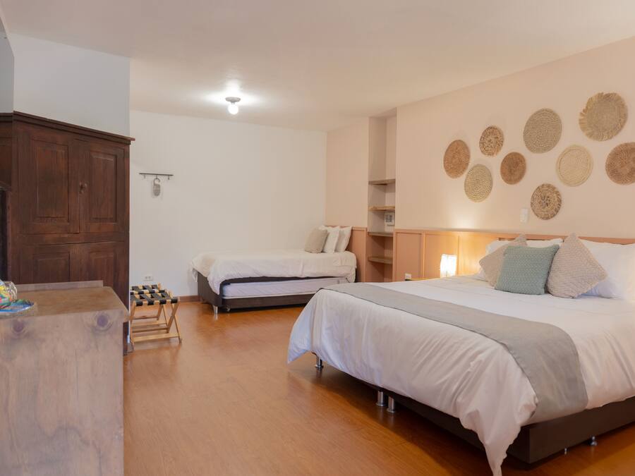 A bedroom with two beds, wooden flooring, a wardrobe, and wall decorations.