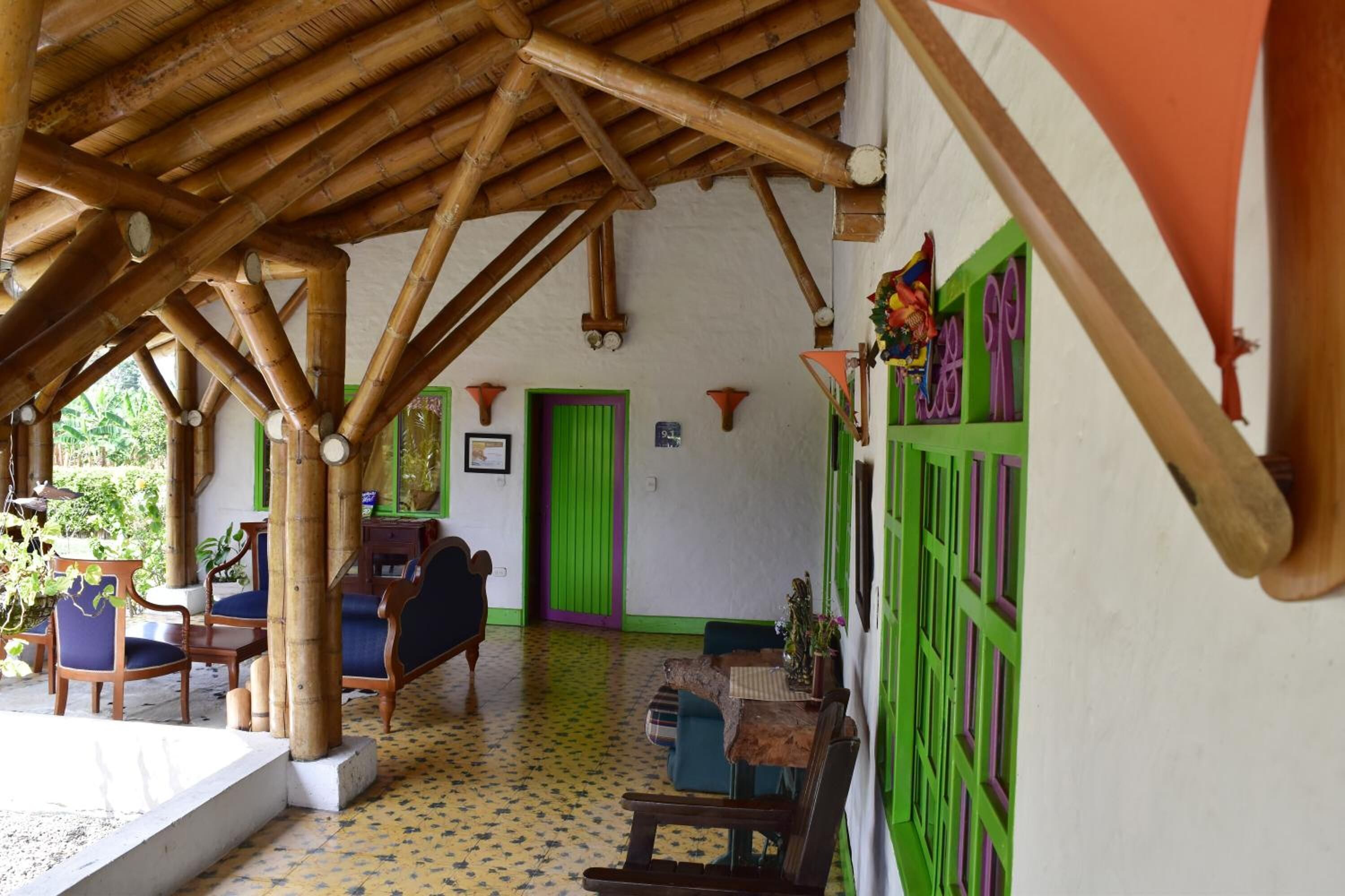 A covered outdoor area with bamboo beams, green doors, and wooden furniture.