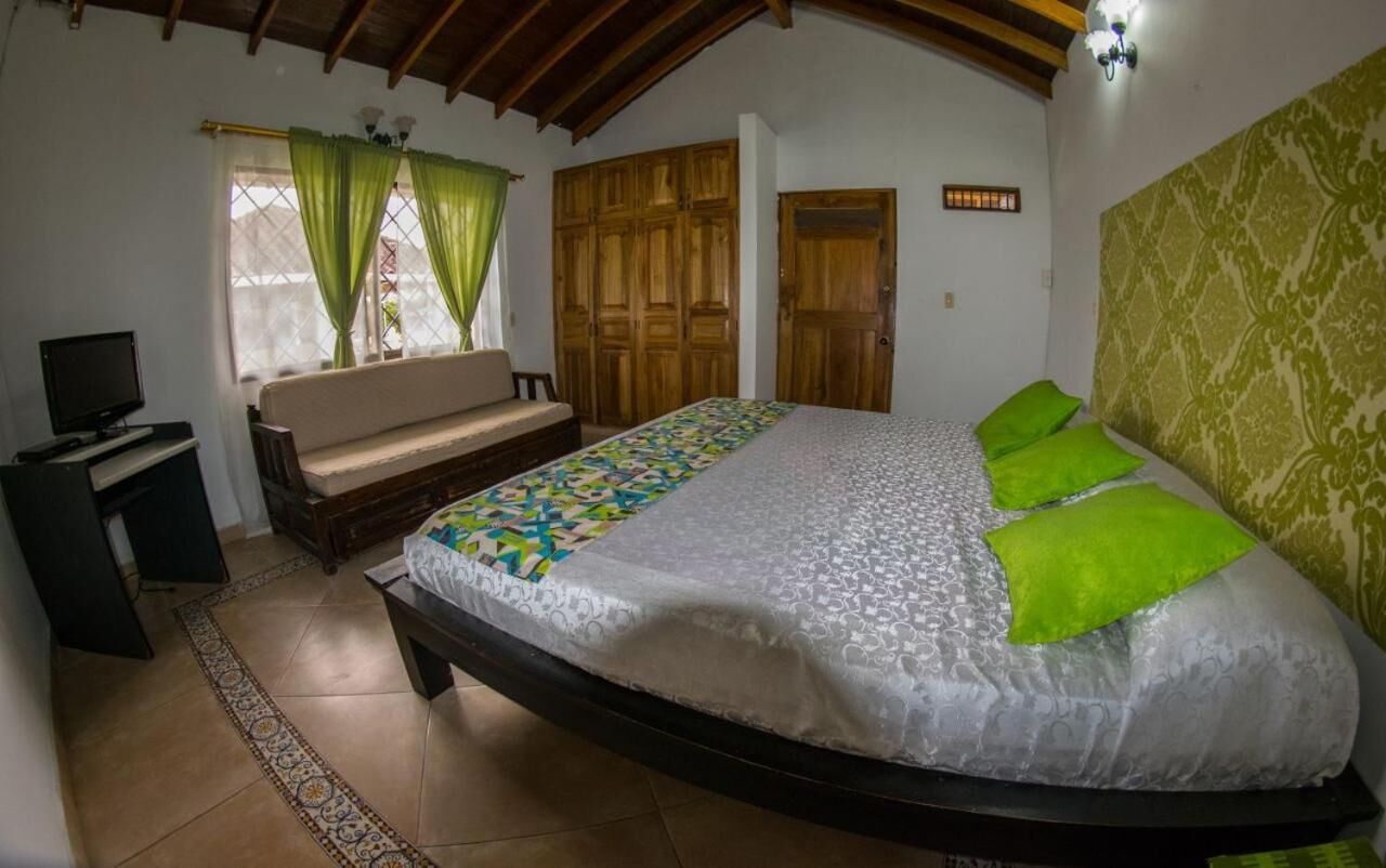 A bedroom with a bed, a sofa, a TV, and a desk.