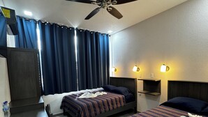 Ein Hotelzimmer mit zwei Betten, einem Schreibtisch, einem Deckenventilator und Wandleuchten.