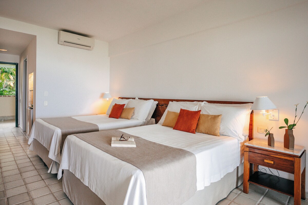 Ein Hotelzimmer mit zwei Betten, einem Nachttisch und einer Lampe.
