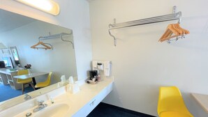 Un baño moderno con un lavamanos blanco, espejo y una silla amarilla.