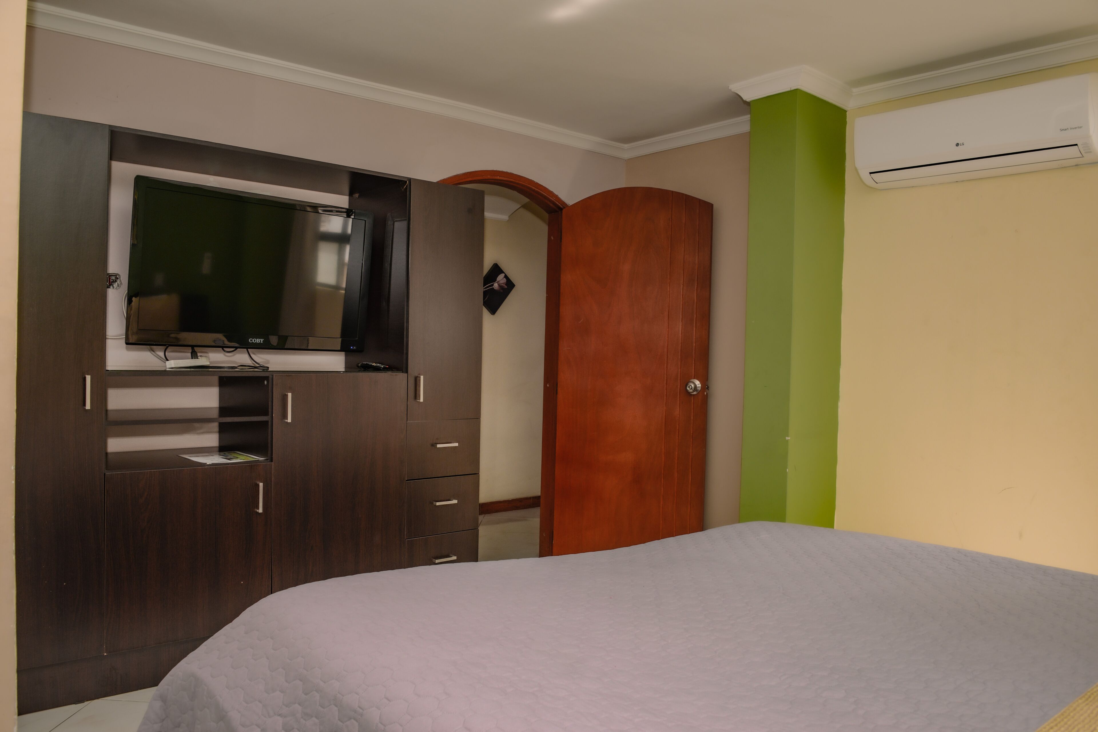 Een slaapkamer met een bed, een kledingkast, een televisie en een airconditioner.