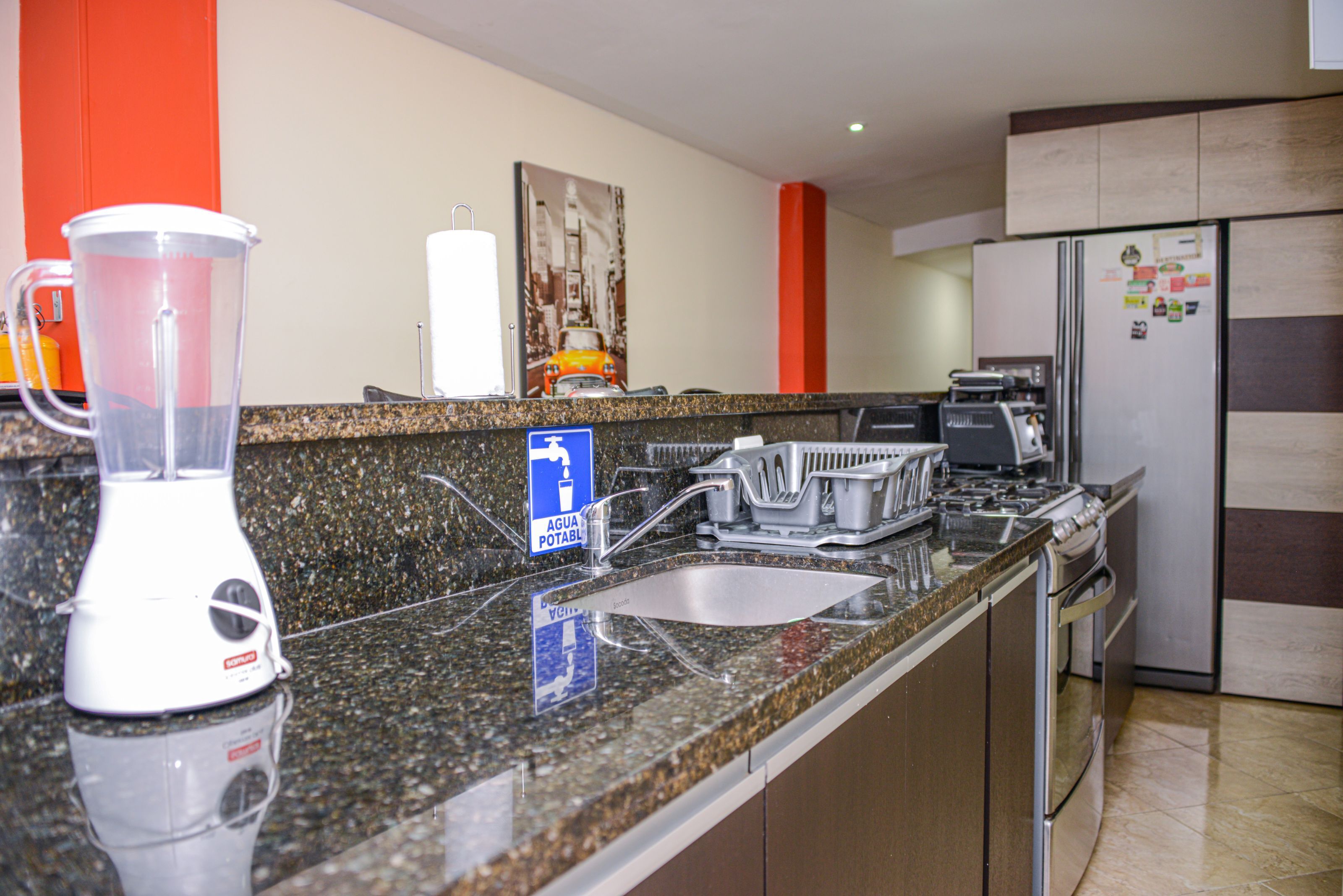 A kitchen with granite countertops, a blender, a sink, and a refrigerator.