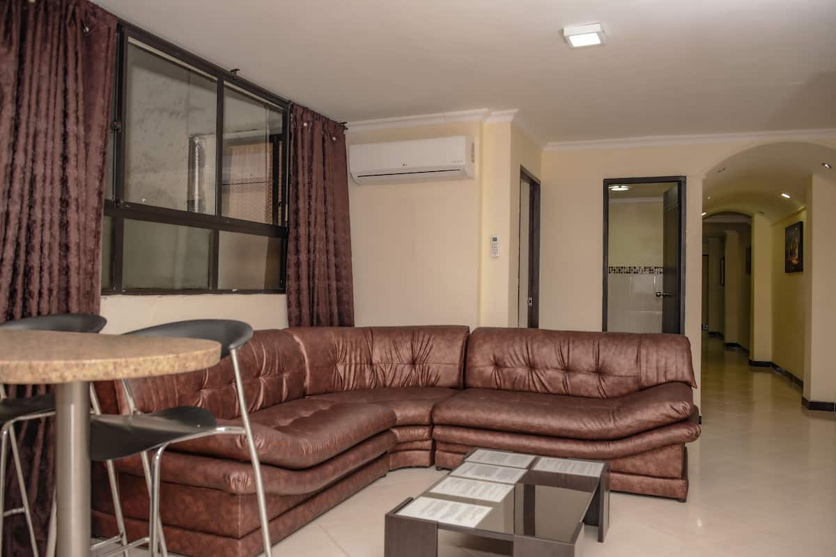 A living room with a brown leather sectional sofa, a small round table, and a glass coffee table.