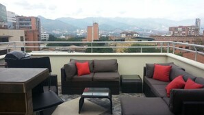 Eine Dachterrasse mit einer Sofagruppe, einem Tisch und Stühlen.