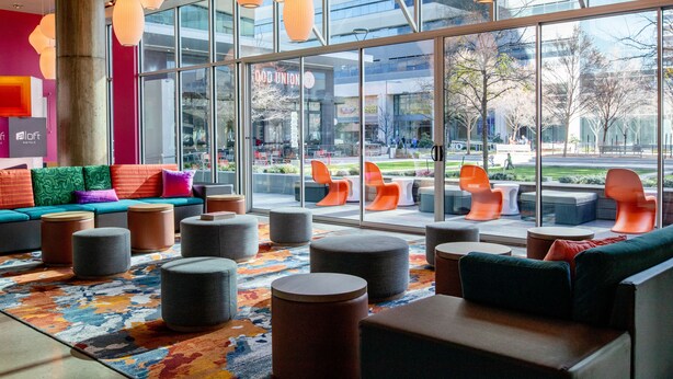 A modern lobby with large windows, colorful seating, and a vibrant rug.