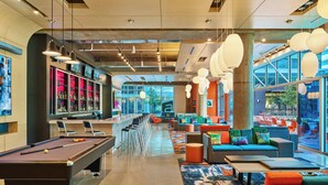 A modern lounge area with a pool table, seating, and a bar.