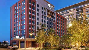 A modern hotel with a prominent 'aloft' sign, multiple floors, and a well-lit entrance area.