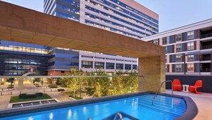 A rooftop pool with a clear view of the surrounding buildings, a modern architectural design, and a well-maintained landscape.