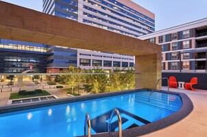 Una piscina en la azotea con vistas despejadas de los edificios circundantes, un diseño arquitectónico moderno y un paisaje bien cuidado.