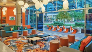 A modern lobby with a large seating area, a colorful rug, and large windows offering a view of the outdoors.