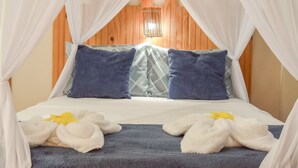 Una cama con dosel blanco, almohadas azules y una manta azul.