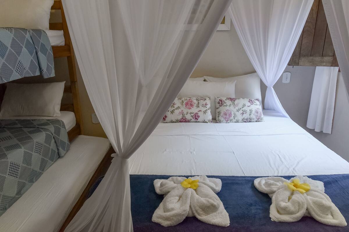 Una habitación de hotel con una cama, una cama adicional o sofá, y una cama con dosel.