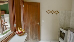 Una cocina con puerta de madera, una encimera con frutero y un horno blanco.