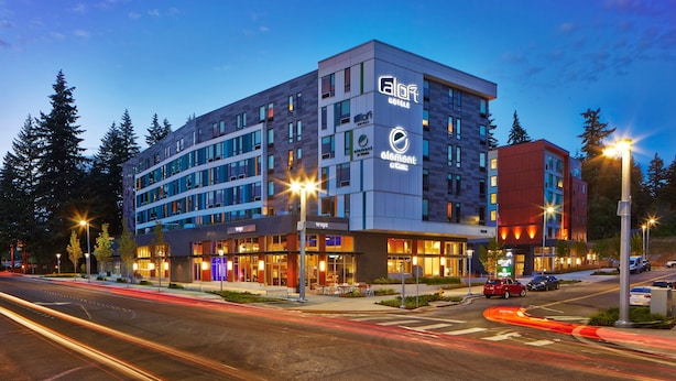 A modern hotel with multiple floors, outdoor seating, and a prominent logo. - Element by Marriott Seattle Redmond (Redmond)