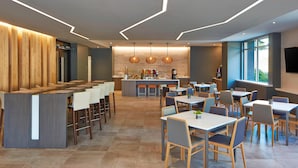 A modern restaurant with a bar area, multiple dining tables, and a kitchen in the background. - Element by Marriott Seattle Redmond (Redmond)