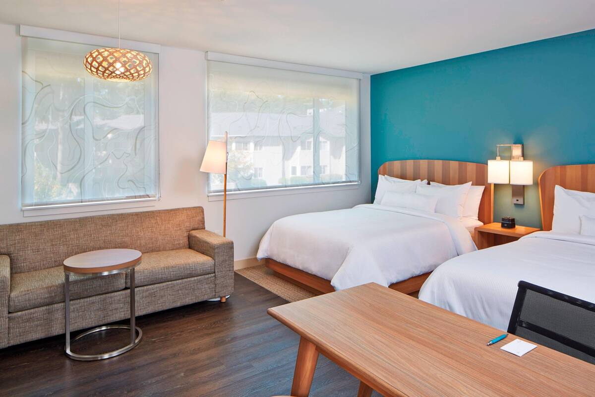 Una habitación de hotel con dos camas, un sofá, una mesita y un escritorio.