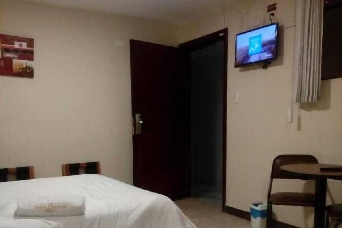 Una habitación de hotel con dos camas, un televisor en la pared y una puerta que da a otra habitación.