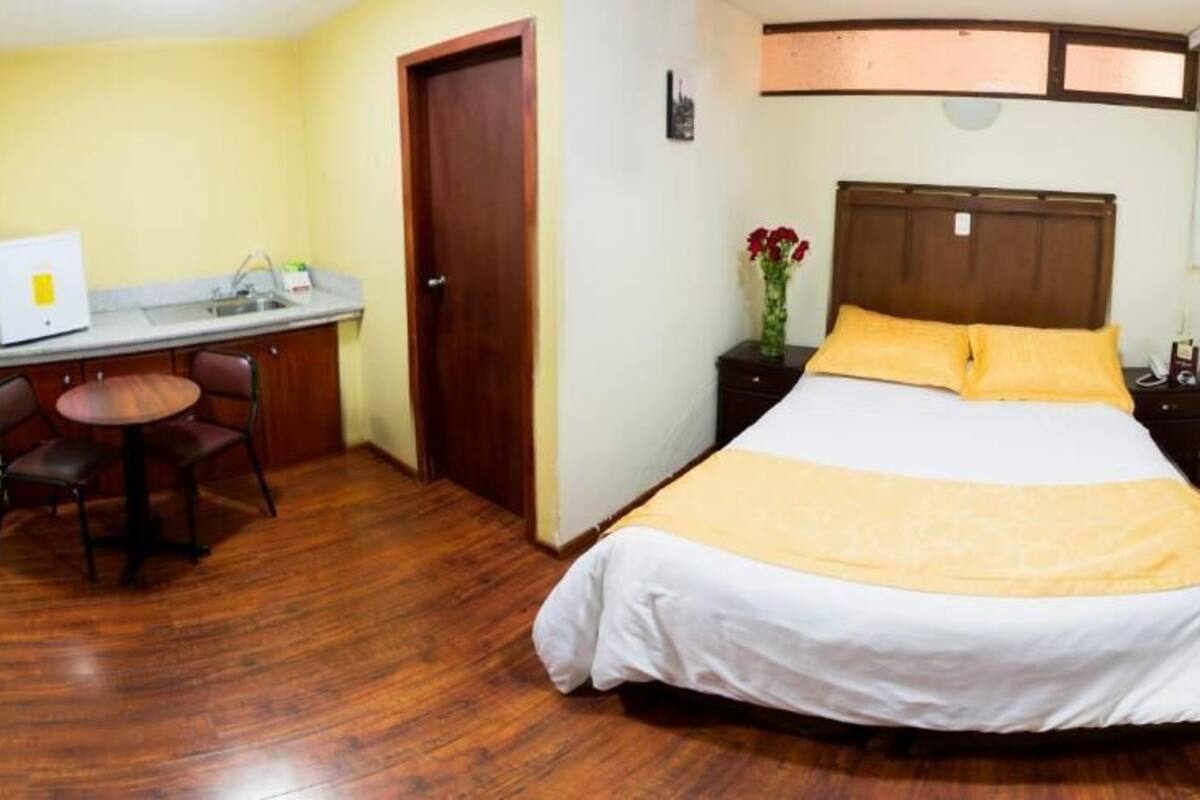 Un dormitorio con cama, escritorio y silla.