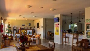 Amplia sala de estar con una mesa de comedor, sillas, un árbol de Navidad y una zona de cocina con barra.