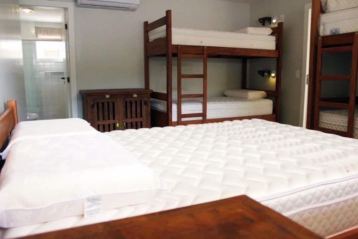 A bunk bed room with a wooden ladder, a small wooden cabinet, and a white mattress.